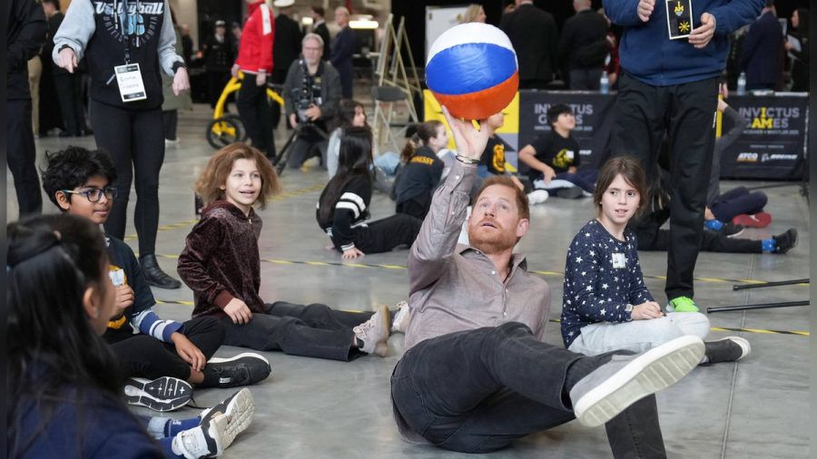 So geht's: Prinz Harry machte den Kindern vor, wie man Sitzvolleyball spielt. (ae/spot)